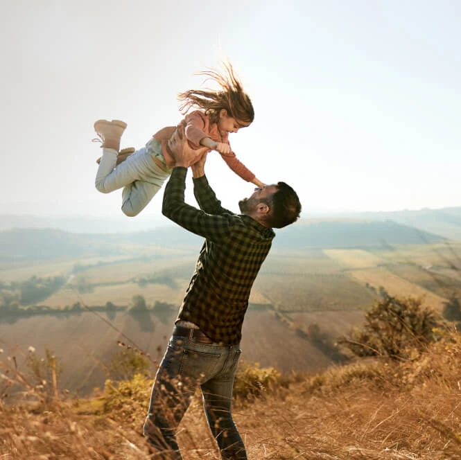 Father holding his child in a prairie with hills in the background